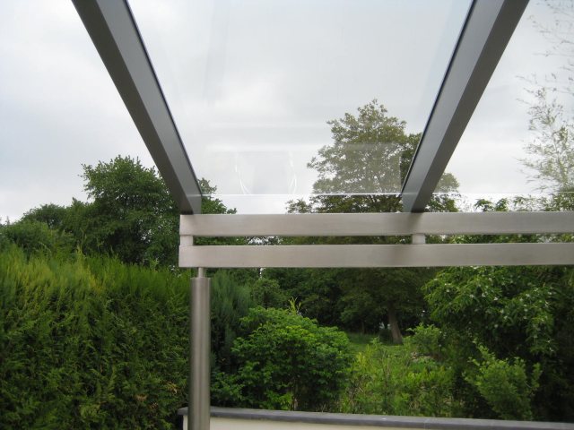 Ein Glasterrassendach vor Sträuchern